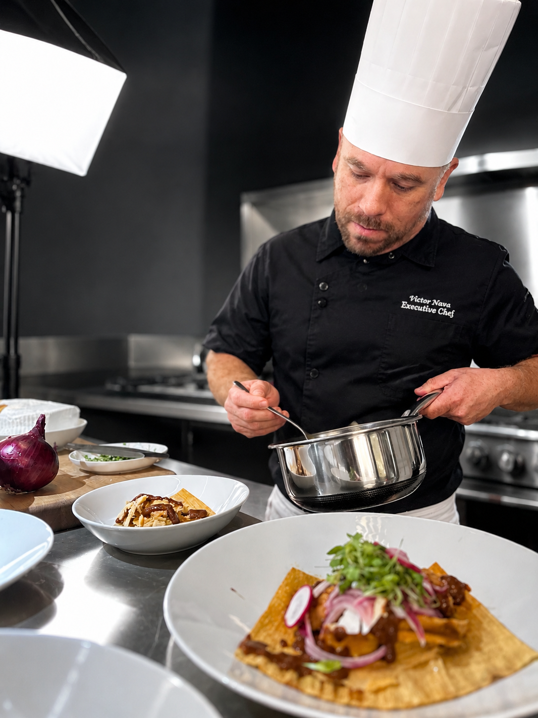 Chef Nava finishing a plated dish in the kitchen